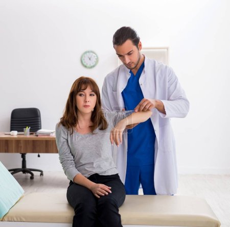 Photo for Young male doctor checking woman joint - Royalty Free Image
