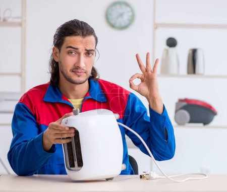Photo for The young male contractor repairing toaster at workshop - Royalty Free Image