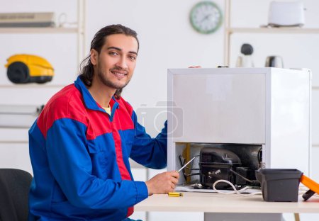 Photo for The young male contractor repairing refrigerator at workshop - Royalty Free Image