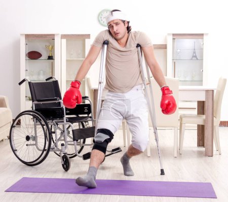 Foto de El joven herido haciendo ejercicios en casa - Imagen libre de derechos