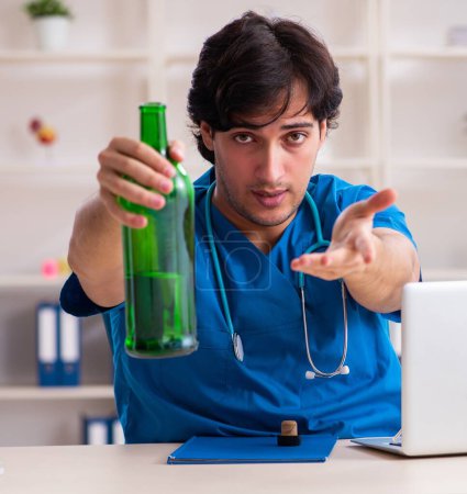 Téléchargez les photos : Le jeune médecin homme buvant au bureau - en image libre de droit