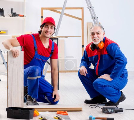 Foto de Los dos contratistas profesionales que ponen el suelo en casa - Imagen libre de derechos