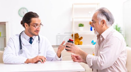 Photo for The young male doctor visiting old patient at home - Royalty Free Image