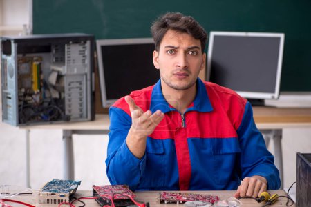 Photo for Young repairman repairing computers in the classroom - Royalty Free Image