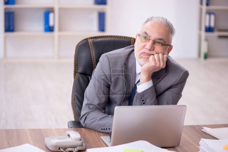Téléchargez les photos : Old businessman employee unhappy with excessive work at workplace - en image libre de droit