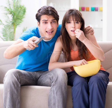 Téléchargez les photos : Le jeune homme regardant le football avec sa femme à la maison - en image libre de droit