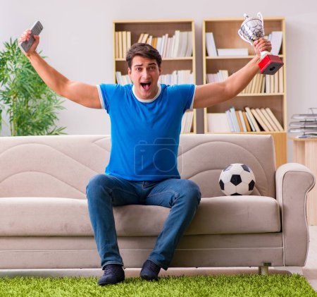 Foto de El hombre viendo fútbol en casa sentado en el sofá - Imagen libre de derechos