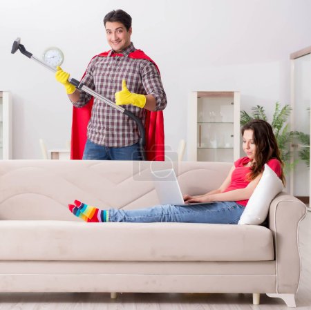 Téléchargez les photos : Le mari super-héros aidant sa femme à la maison - en image libre de droit