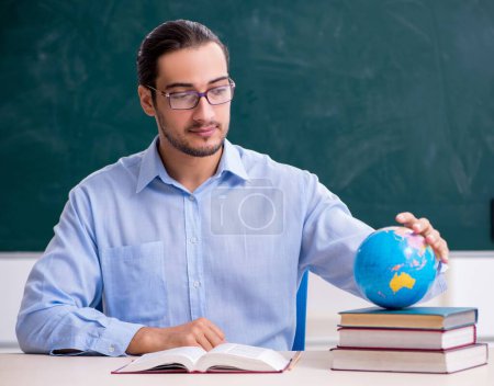 Photo for Young geography teacher in front of blackboard - Royalty Free Image