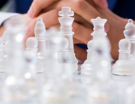 Téléchargez les photos : Le jeune homme d'affaires jouant aux échecs en verre au bureau - en image libre de droit