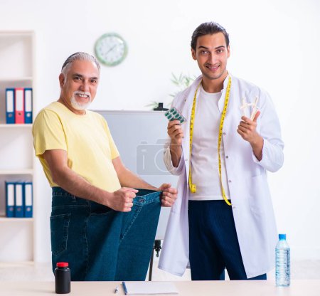 Photo for The doctor dietician and happy patient wearing large trousers - Royalty Free Image