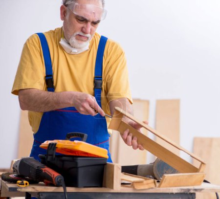 Téléchargez les photos : Le vieil homme charpentier travaillant en atelier - en image libre de droit