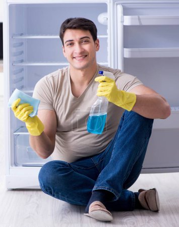 Téléchargez les photos : L'homme de nettoyage réfrigérateur dans le concept d'hygiène - en image libre de droit