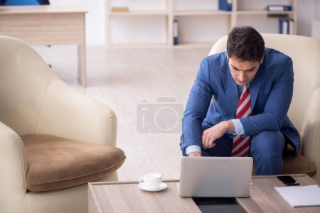 Foto de Empleado joven empresario sentado en el lugar de trabajo - Imagen libre de derechos
