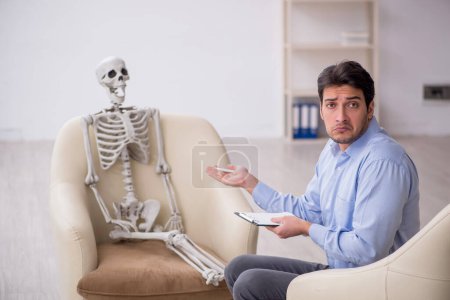 Foto de Joven psicólogo reunión con esqueleto - Imagen libre de derechos