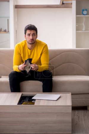 Téléchargez les photos : Young male student sitting at home in remuneration concept - en image libre de droit