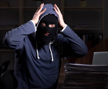 Photo for The male thief in balaclava in the office night time - Royalty Free Image
