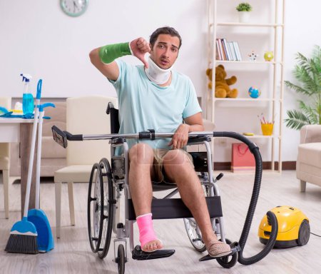 Photo for The young man in wheel-chair cleaning the house - Royalty Free Image