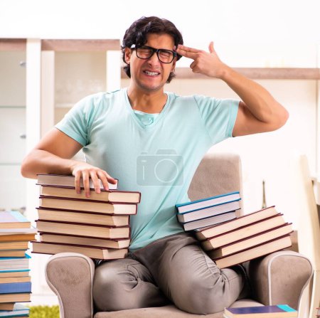 Foto de The male student with many books at home - Imagen libre de derechos