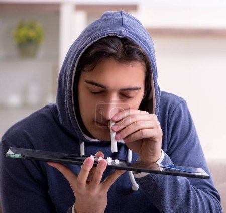 Téléchargez les photos : Le jeune homme ayant des problèmes avec les narcotiques à la maison - en image libre de droit