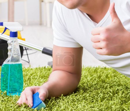 Foto de El joven marido hombre limpieza piso en casa - Imagen libre de derechos