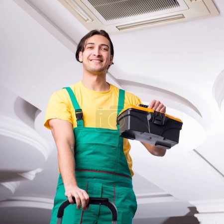 Téléchargez les photos : Le jeune réparateur réparer unité de climatisation de plafond - en image libre de droit