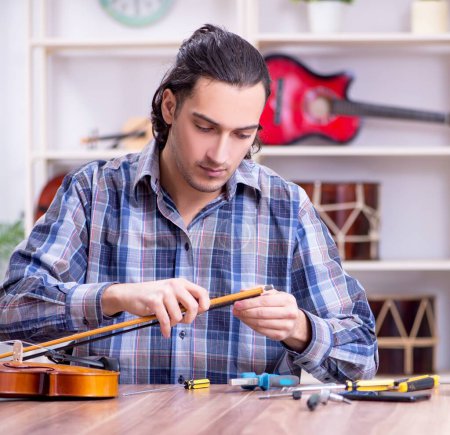 Photo for The young handsome repairman repairing violin - Royalty Free Image