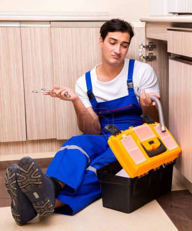 Téléchargez les photos : Le jeune réparateur travaillant à la cuisine - en image libre de droit