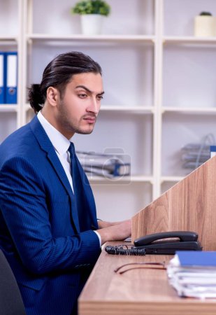 Téléchargez les photos : Le jeune homme d'affaires beau qui travaille dans le bureau - en image libre de droit