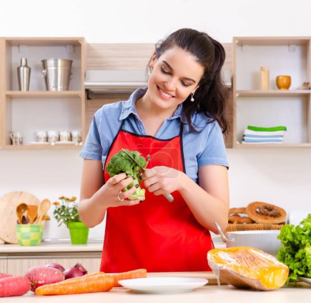 Téléchargez les photos : La jeune femme aux légumes dans la cuisine - en image libre de droit