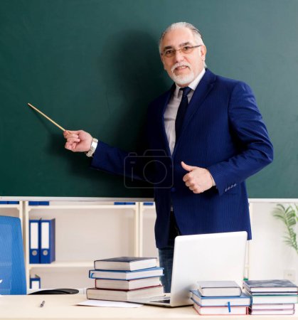Photo for The aged male teacher in front of chalkboard - Royalty Free Image