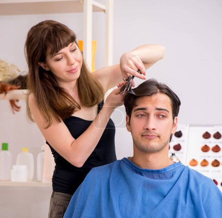 Téléchargez les photos : Les jeunes attirent l'homme visitant le coiffeur féminin - en image libre de droit