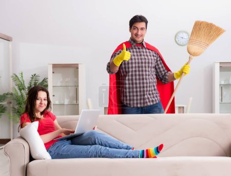 Téléchargez les photos : Le mari super-héros aidant sa femme à la maison - en image libre de droit
