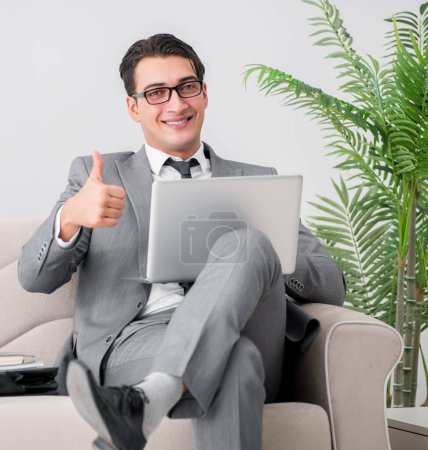 Foto de El hombre de negocios con portátil portátil sentado en el sofá - Imagen libre de derechos