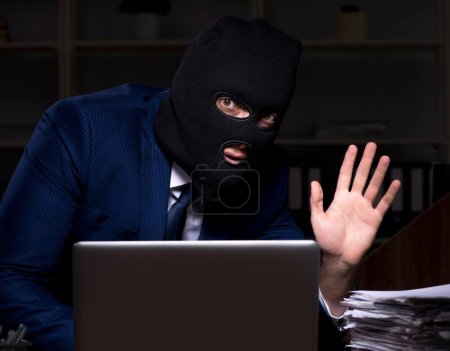 Téléchargez les photos : L'employé masculin vole des informations dans le bureau la nuit - en image libre de droit