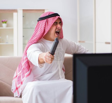 Téléchargez les photos : L'homme d'affaires arabe regardant la télévision à la maison - en image libre de droit