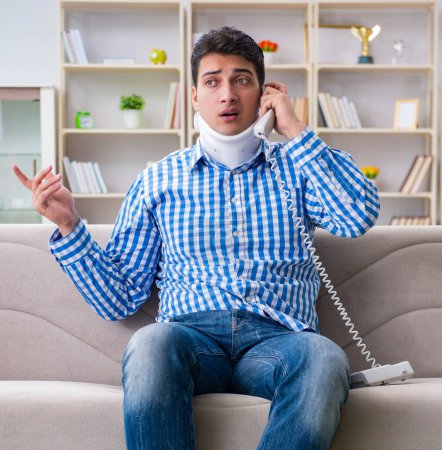 Foto de Hombre con un traumatismo en la columna vertebral del cuello con un cuello cervicouterino ortopédico hablando por teléfono - Imagen libre de derechos