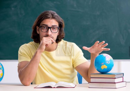 Young geography teacher in front of blackboard