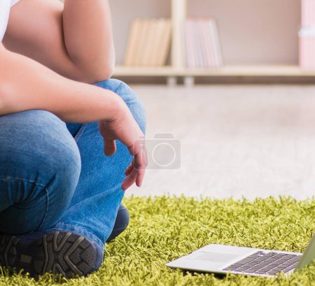 Foto de El hombre que trabaja en el portátil en casa en el suelo de la alfombra - Imagen libre de derechos