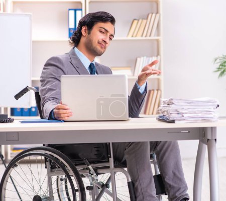 Téléchargez les photos : Le jeune et beau employé en fauteuil roulant au bureau - en image libre de droit