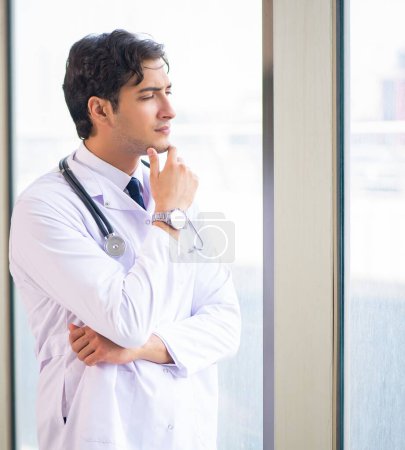 Téléchargez les photos : Le jeune beau docteur debout à la fenêtre - en image libre de droit