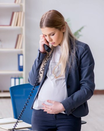 Foto de La empleada embarazada en la oficina - Imagen libre de derechos