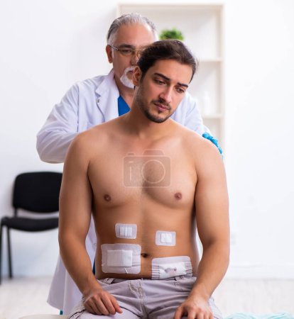Téléchargez les photos : Homme blessé visitant médecin masculin expérimenté - en image libre de droit