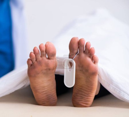 Téléchargez les photos : Un coroner de police examine un cadavre à la morgue - en image libre de droit