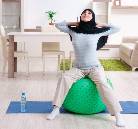 Photo for The young woman in hijab doing exercises at home - Royalty Free Image