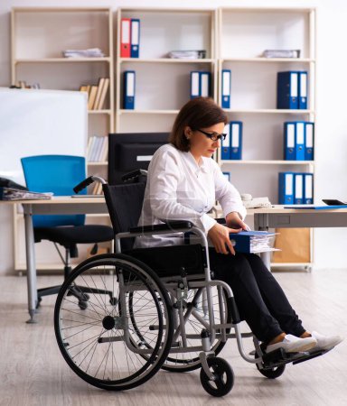 Téléchargez les photos : L'employée en fauteuil roulant au bureau - en image libre de droit