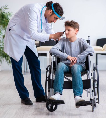 Téléchargez les photos : Le jeune homme médecin pédiatre et garçon en fauteuil roulant - en image libre de droit
