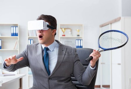 Photo for Businessman playing virtual reality tennis in office with VR goggle - Royalty Free Image