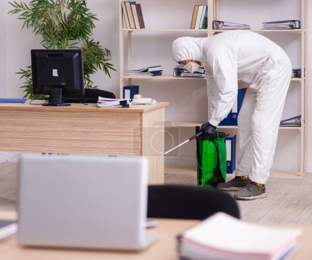 Photo for Contractor disinfecting office for the COVID-19 coronavirus - Royalty Free Image