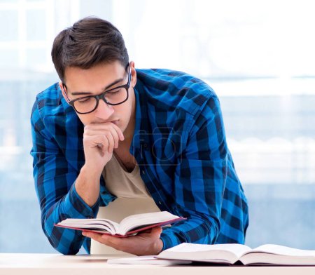 Téléchargez les photos : Étudiant étudiant dans la bibliothèque vide avec un livre se préparant à l'examen - en image libre de droit